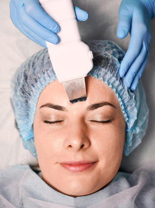 Woman receiving ultrasonic facial treatment at clinic